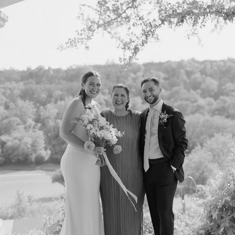 Marisa with the bride and groom beneath a white pergola overlooking the water